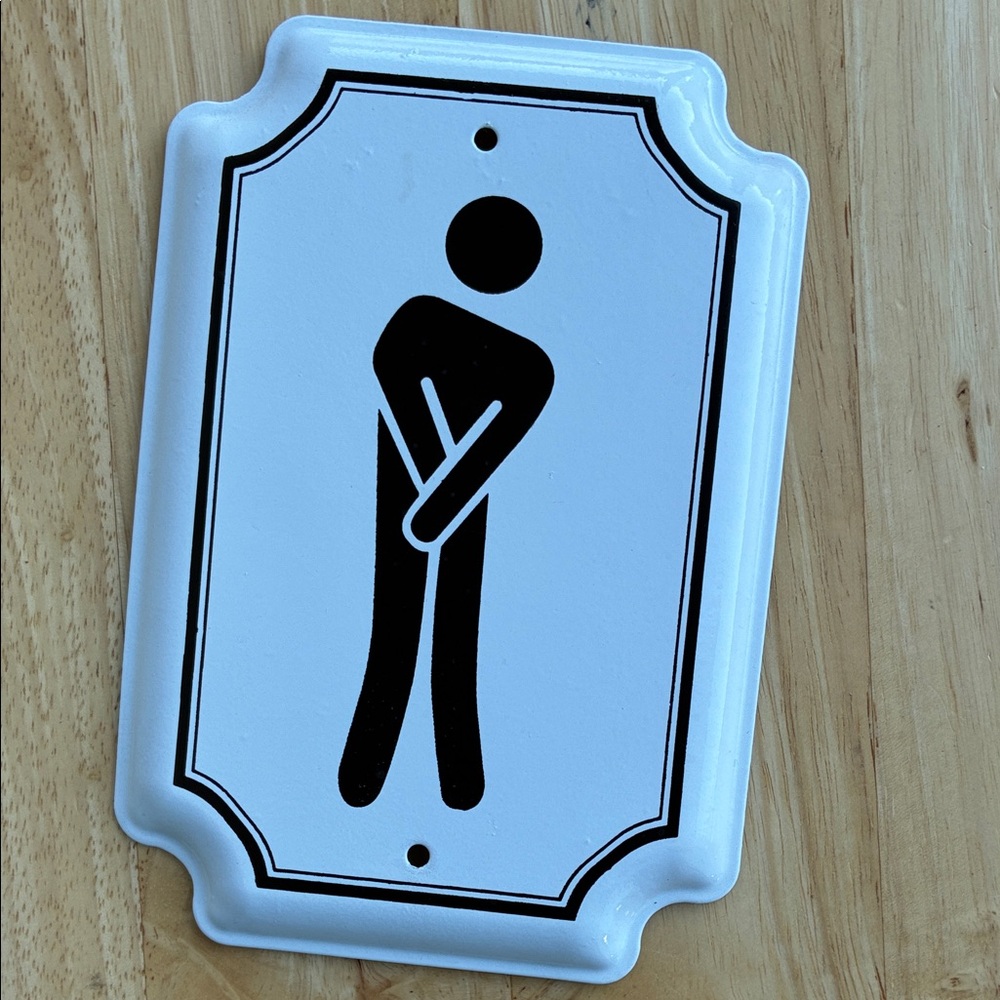 Bathroom sign. White with black graphic on enameled metal